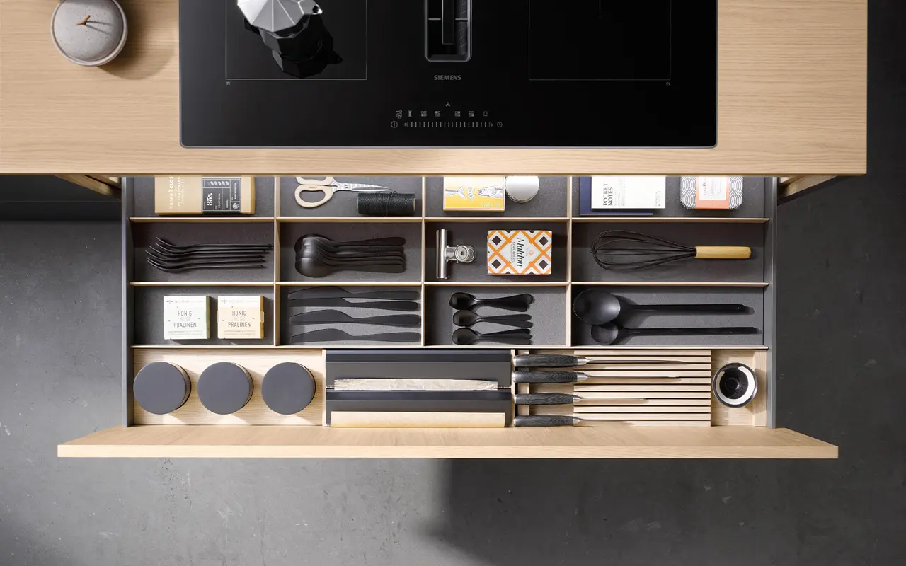 Übersichtlich sortierte Küchenschublade mit Besteck, Messern und Küchenutensilien. Hochwertiger Holzeinsatz für Ordnung und Stil in modernen Küchen.